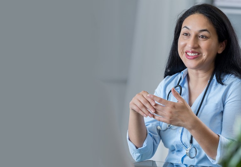 An adult female doctor sits across from her unrecognizable patient.